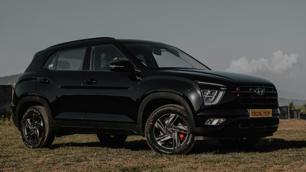 Glossy black Hyundai Creta SUV parked on a green grassy field under a bright clear sky representing a popular budget luxury family car.