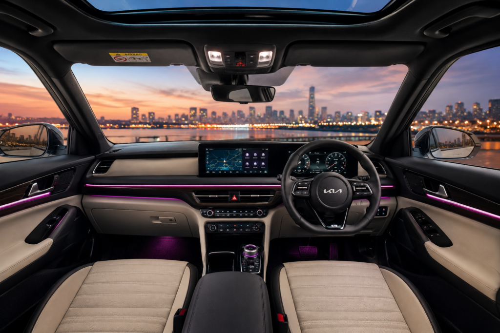 नई Kia Seltos Hybrid का लग्जरी इंटीरियर और डैशबोर्ड, जिसमें बड़ा टचस्क्रीन और एम्बिएंट लाइटिंग दिख रही है