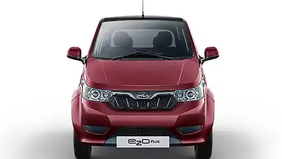 सफेद बैकग्राउंड पर लाल रंग की Mahindra e2o Plus इलेक्ट्रिक कार सामने से दिखाई दे रही है। कार के फ्रंट ग्रिल, हेडलाइट्स और बीच में लगा Mahindra लोगो स्पष्ट रूप से नजर आ रहा है।